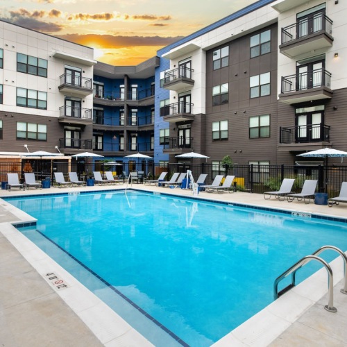 a swimming pool in a courtyard with lounge chairs
