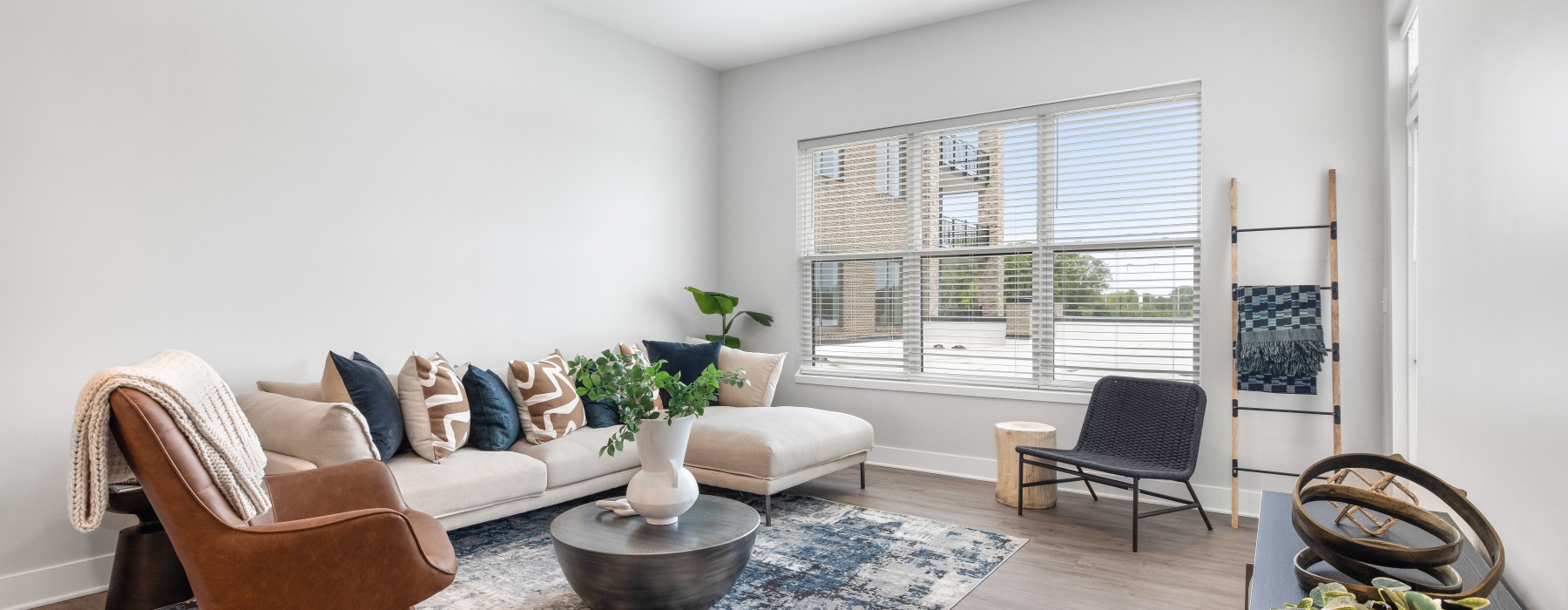 Furnished model apartment featuring a spacious living room with bright natural lighting and large windows