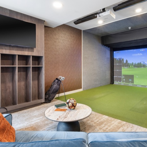 a clubroom with a golf simulator and a couch